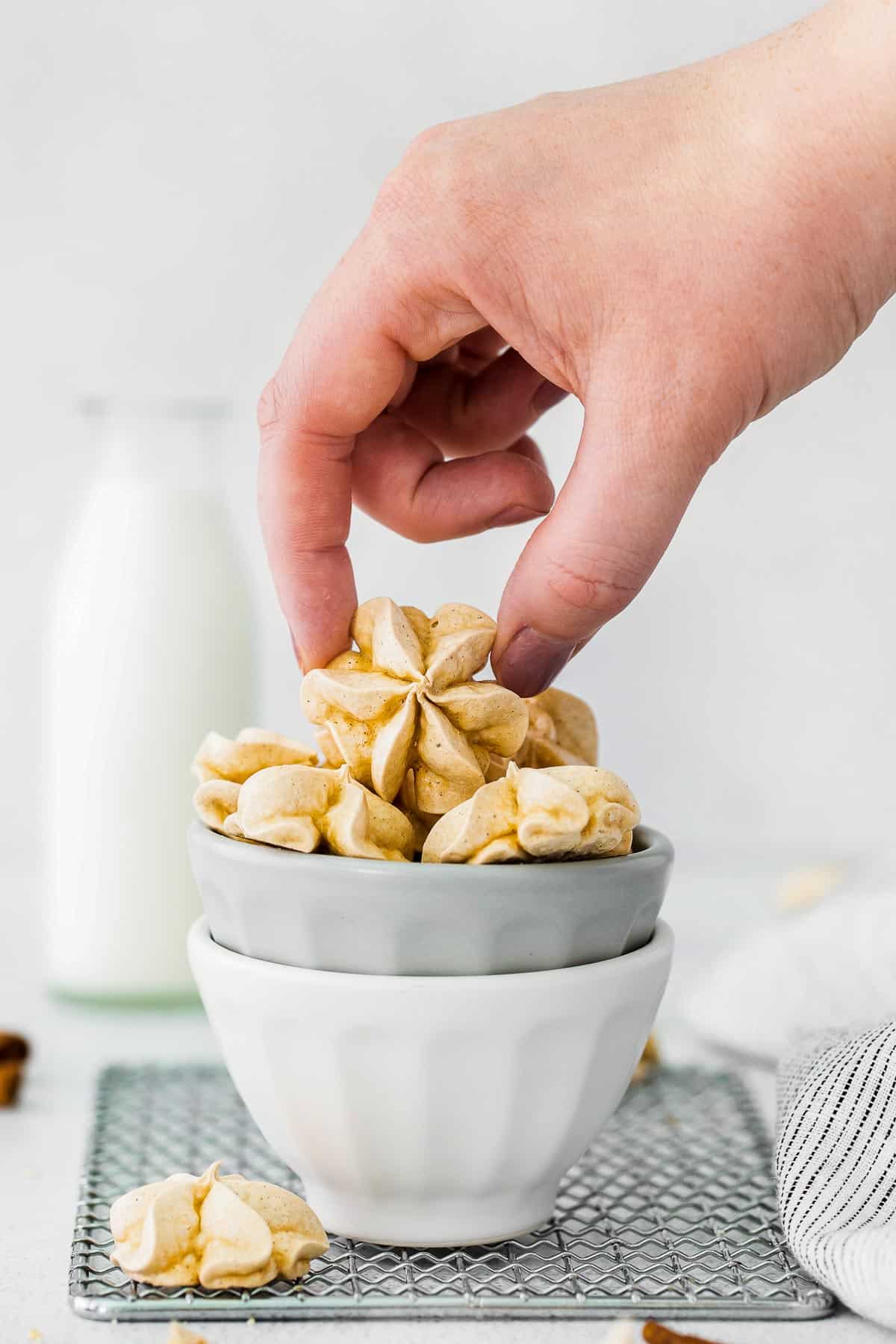 cinnamon meringue cookies in bowl with hand