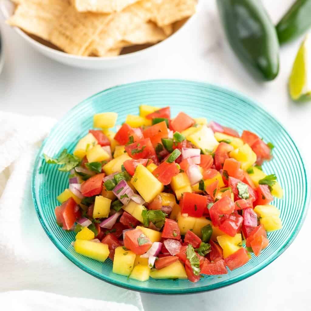 mango pico de gallo in bowl with chips close up