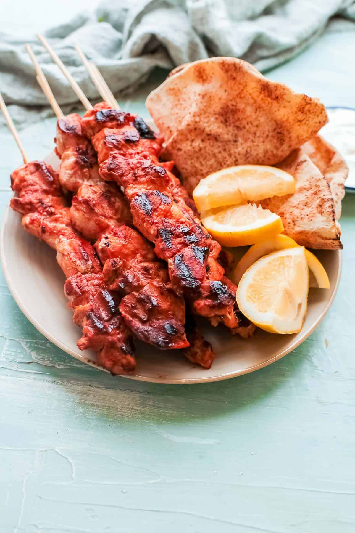 lebanese chicken skewers close up on plate with lemon wedges