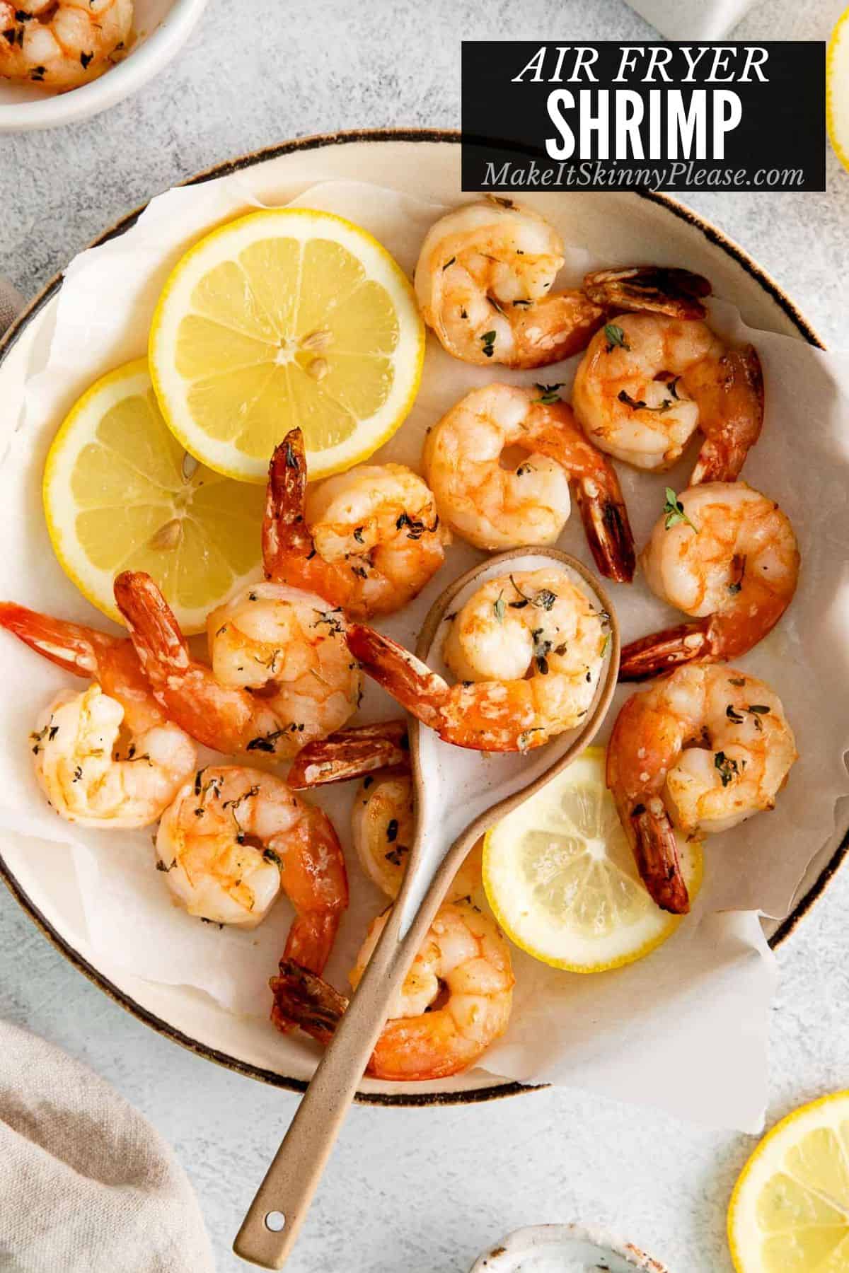 air fryer shrimp in bowl with lemon slices and spoon.