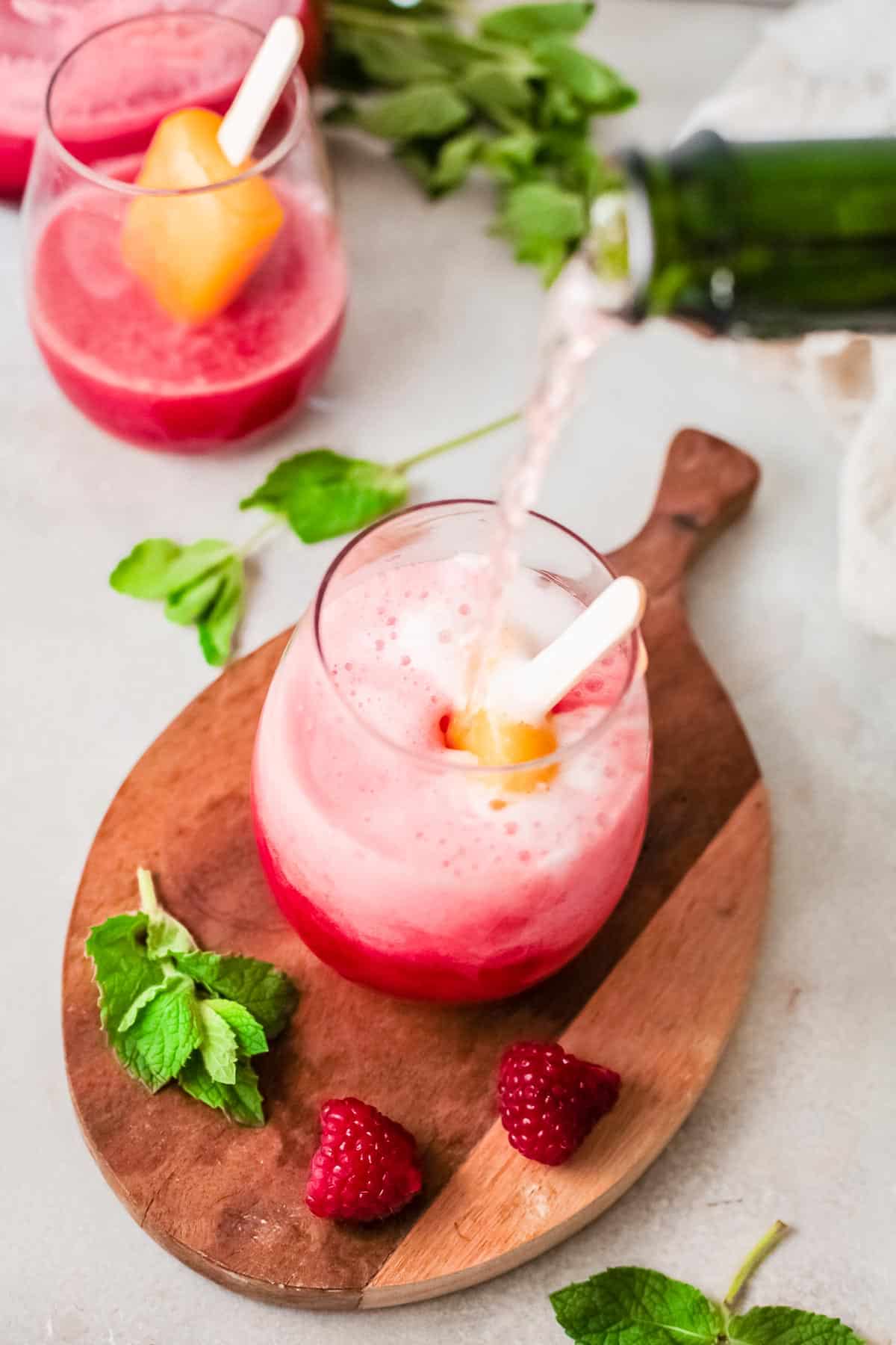 raspberry popsicle cocktail with champagne pouring.