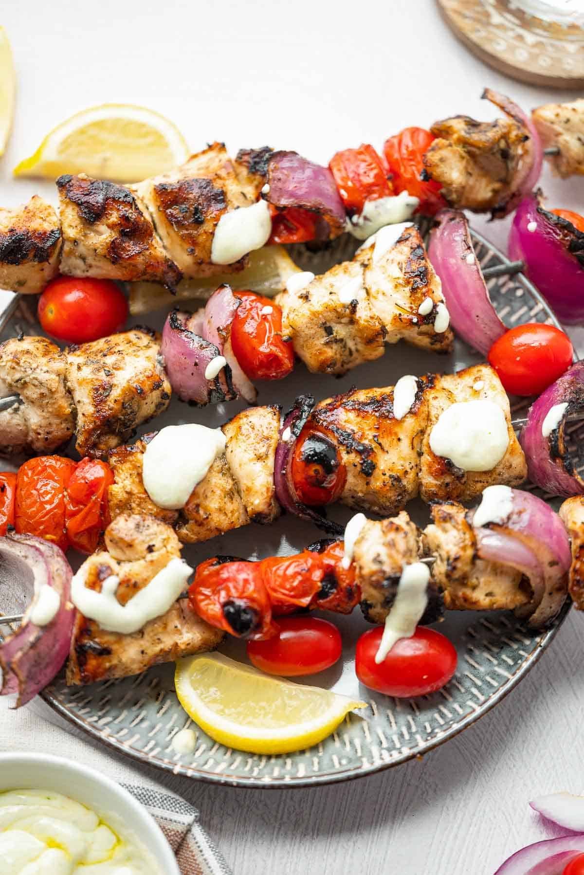 grilled chicken skewers on a plate with dipping sauce.