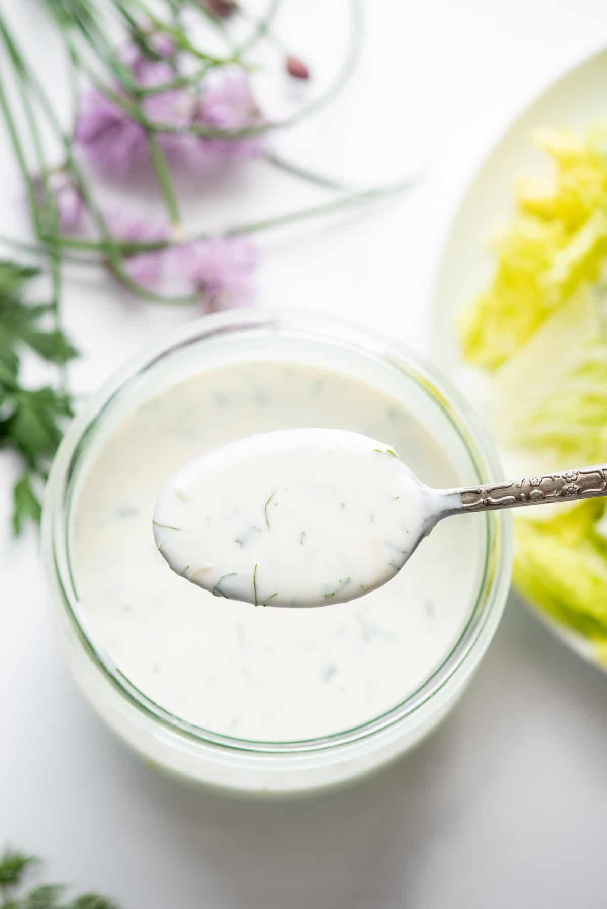 homemade ranch dressing on spoon above jar.