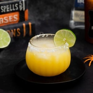 halloween orange margarita in a pumpkin glass side view with lime.