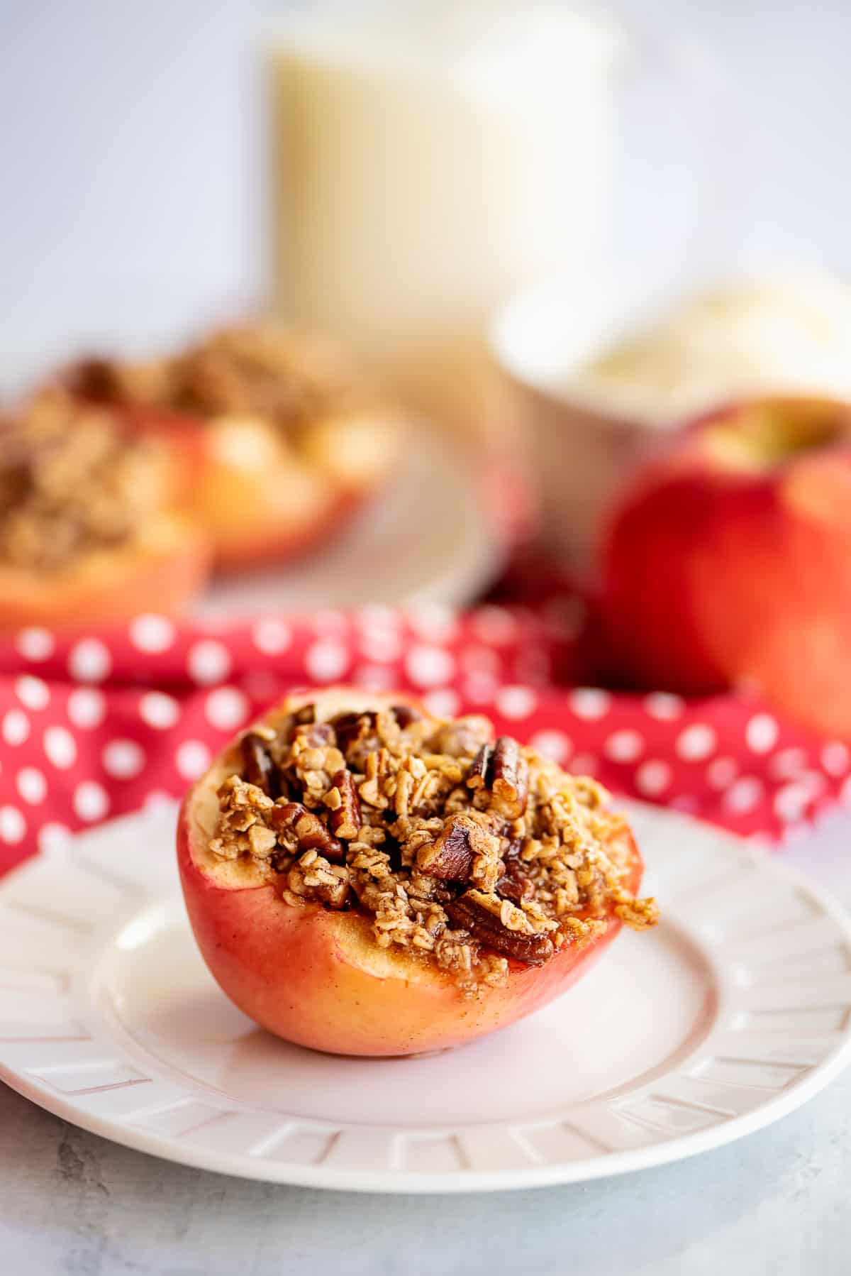 baked apple with crumble topping on white plate.