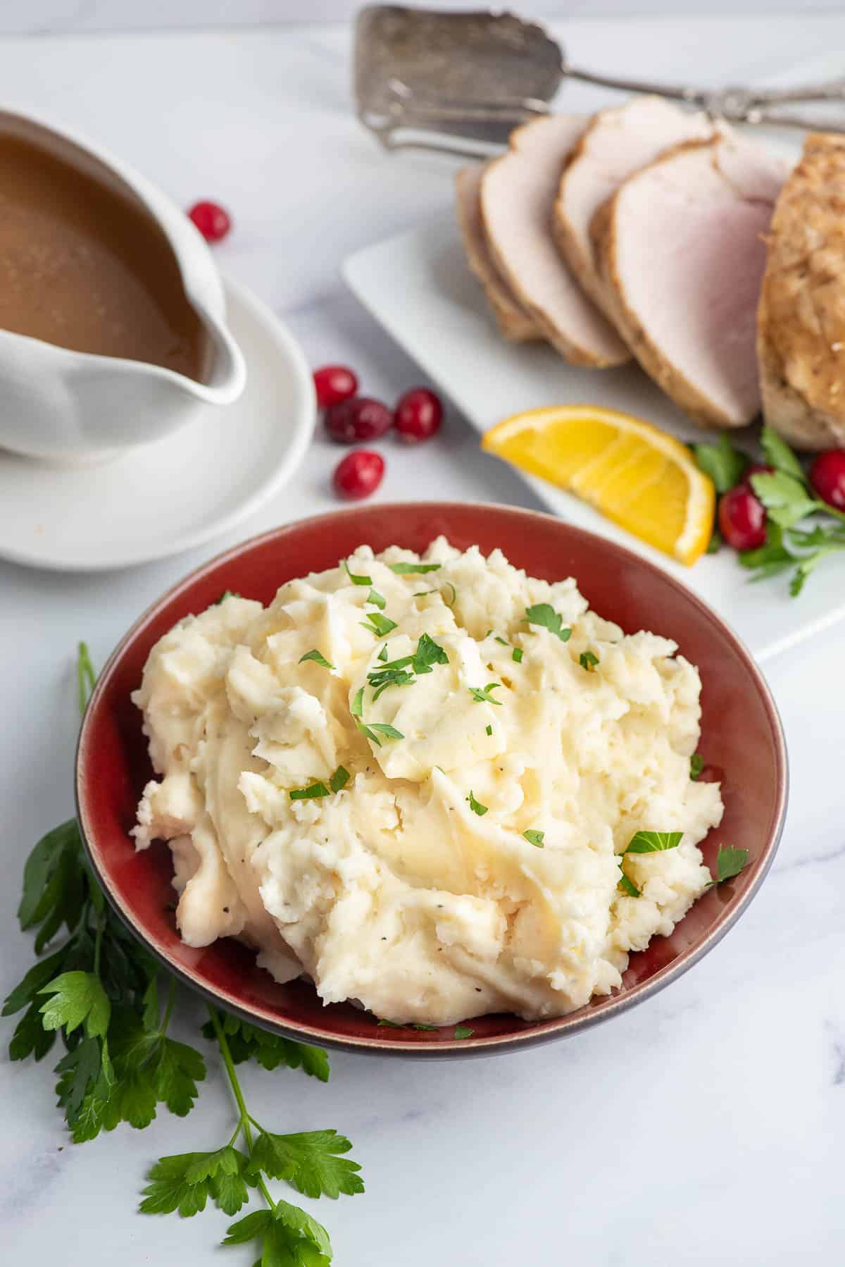 cauliflower mashed potatoes in a red bowl with sliced turkey.