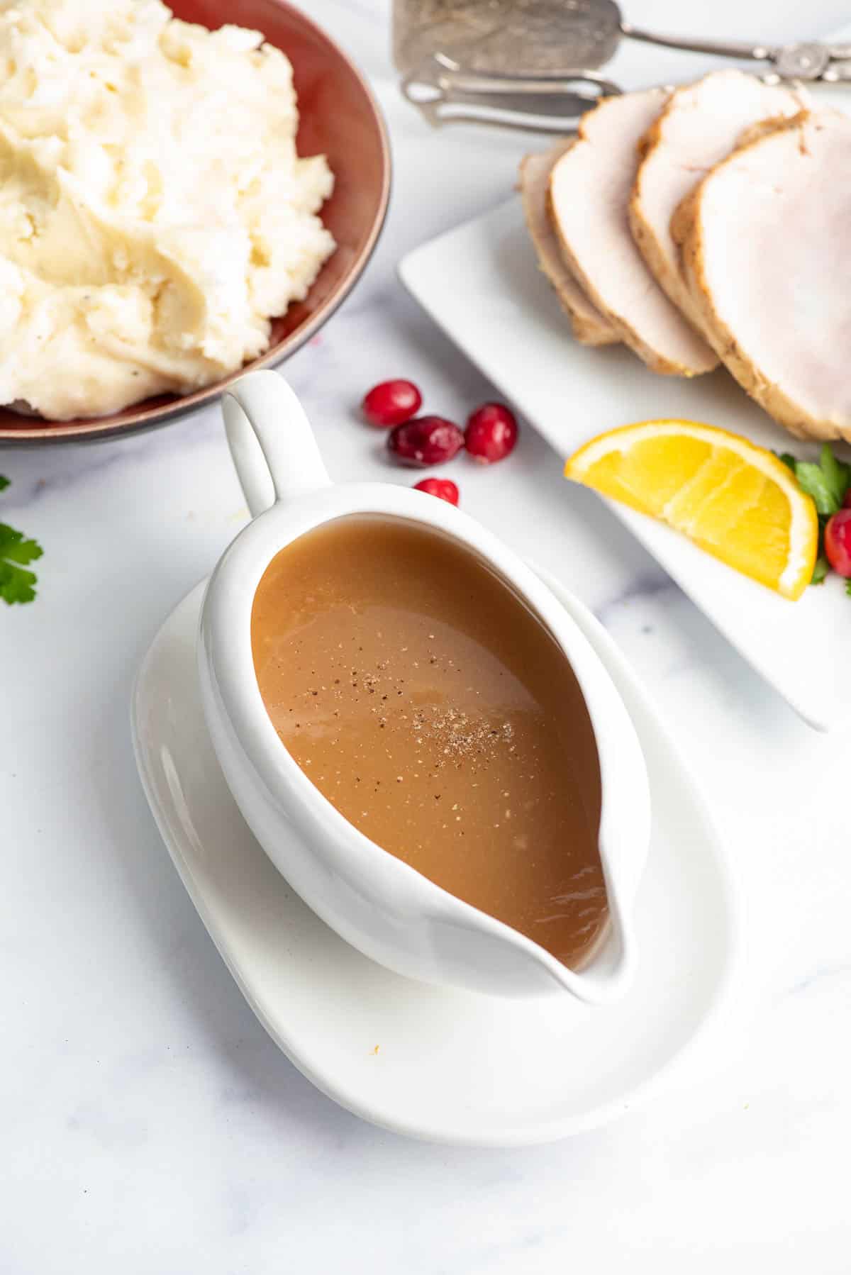 apple cider gravy in a gravy boat with thanksgiving food.