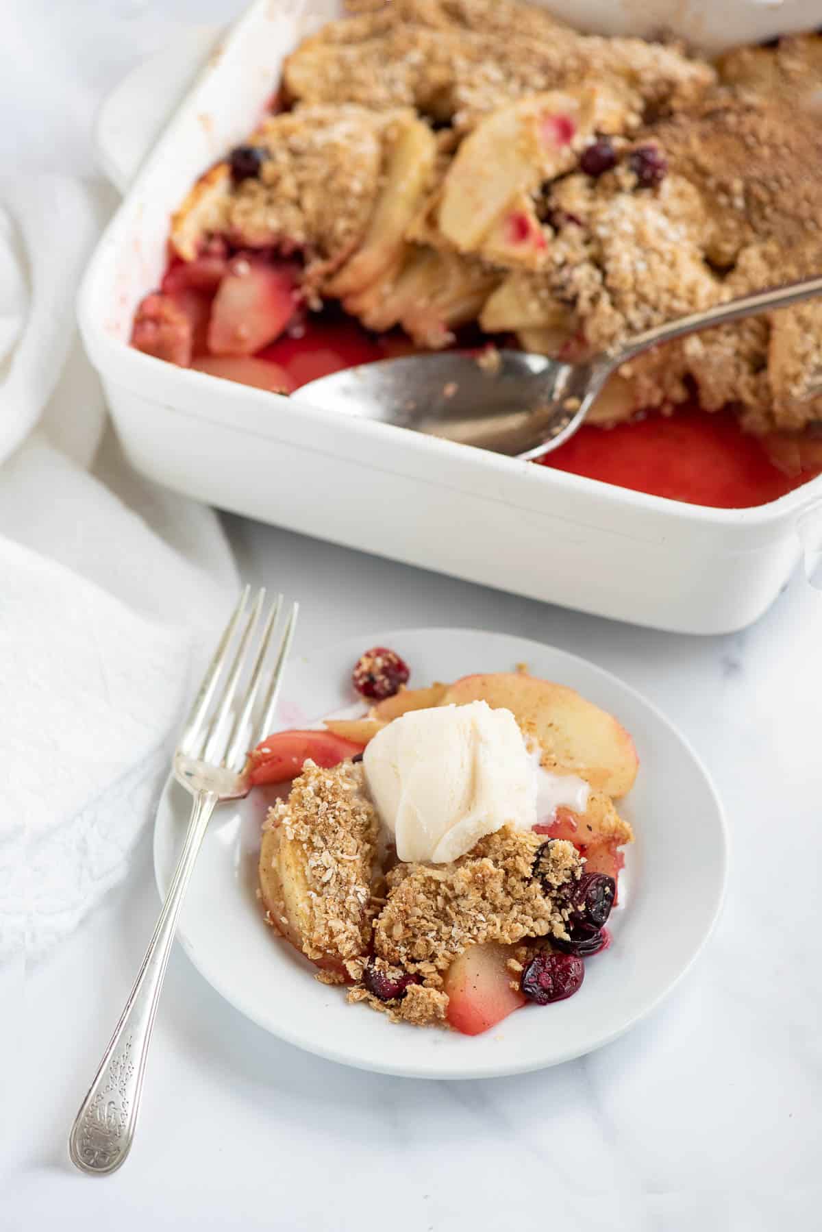apple cranberry crisp in baking dish and serving plate.