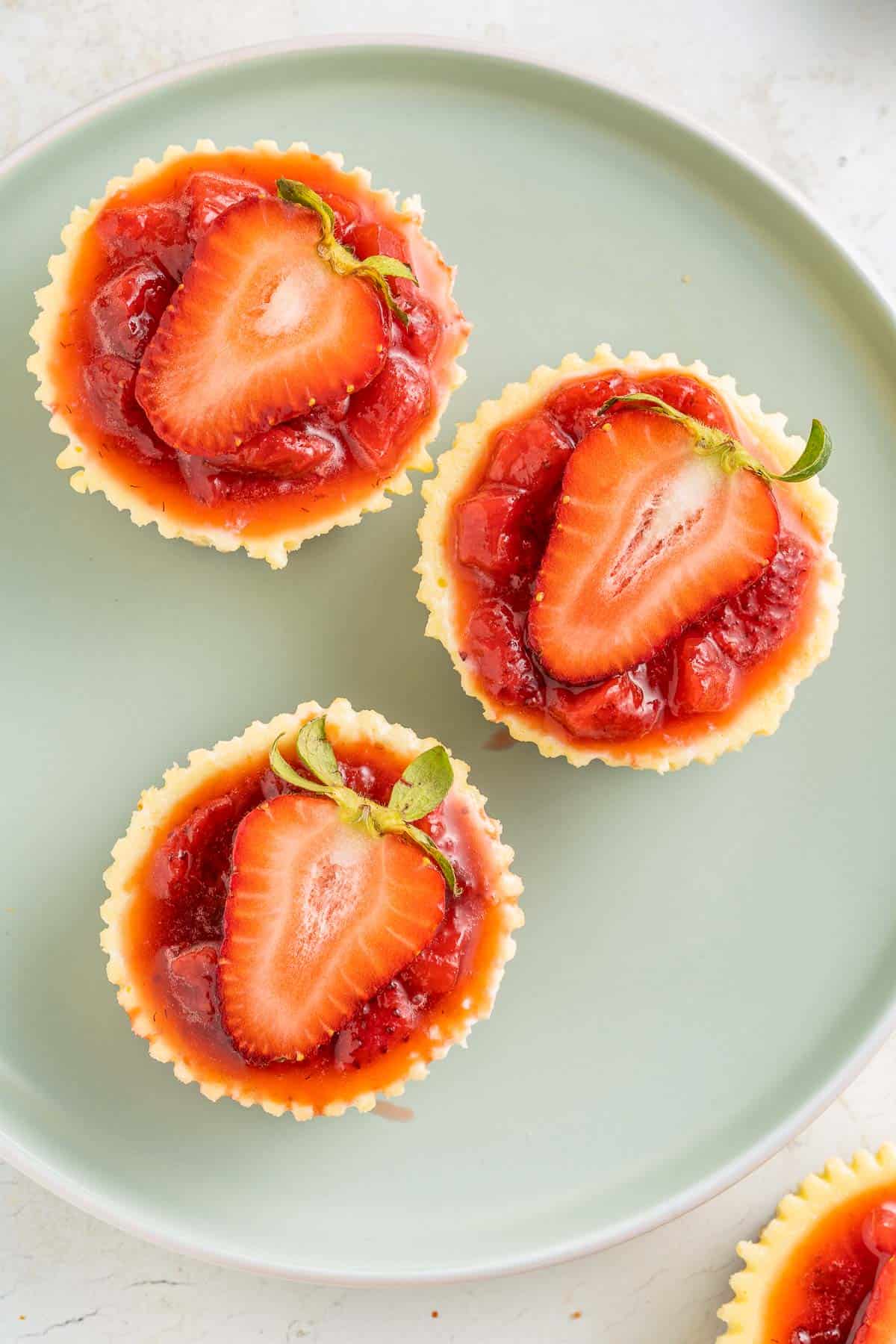 mini cheesecakes with strawberry topping overhead.