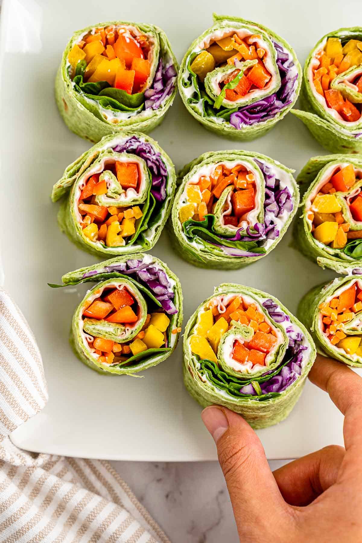 turkey roll ups from above on platter with hand.