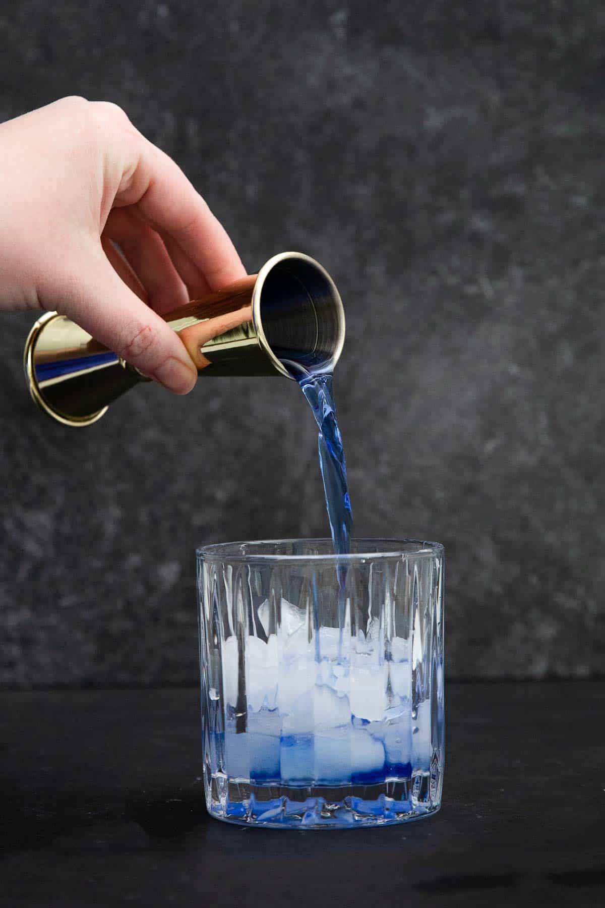 empress gin cocktail pouring gin into glass with ice.